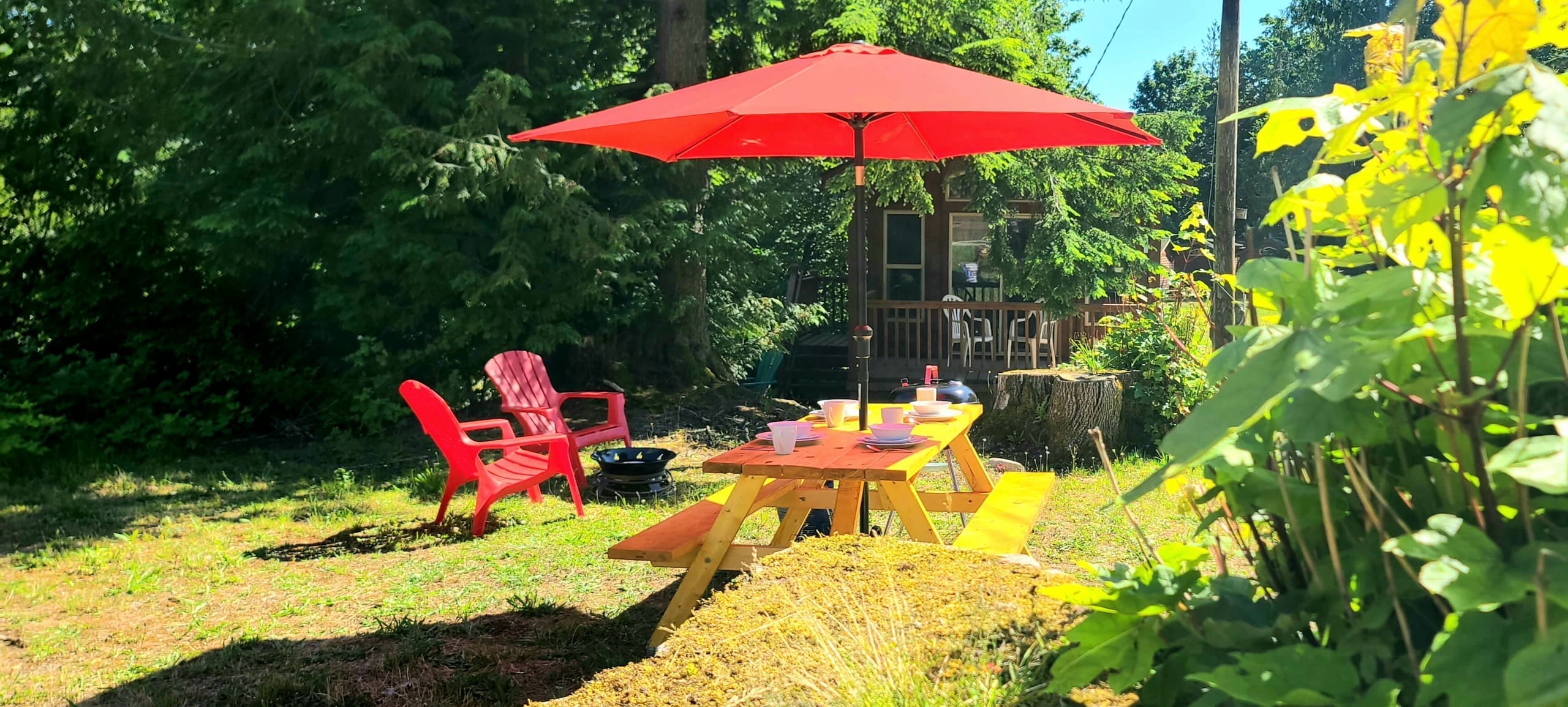 Glamping picnic table set for two beside a red umbrella