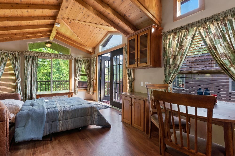 Cabin interior with a sofa bed, dining nook, and vaulted cedar ceiling