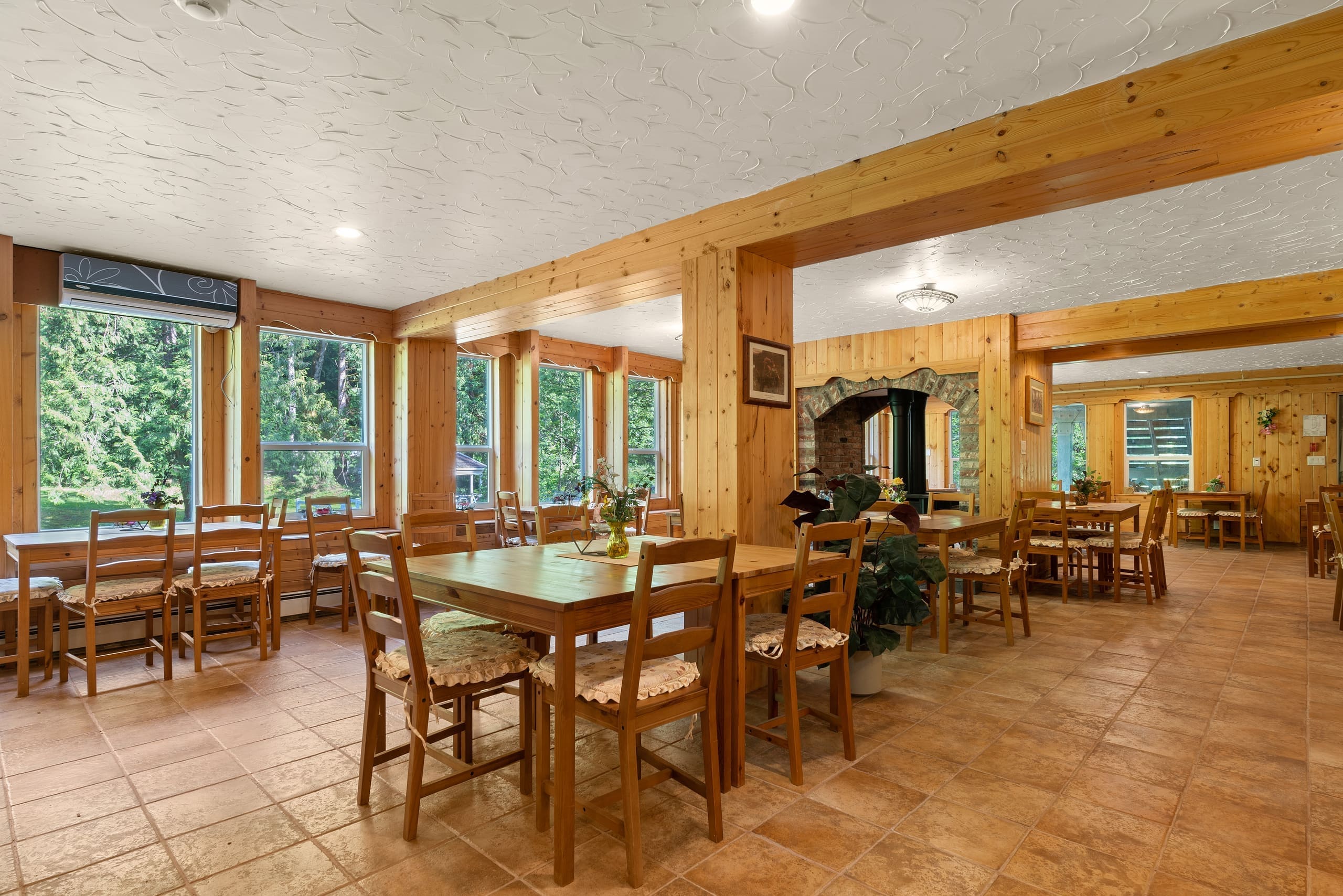Lodge dining room with wood beams and a stone fireplace