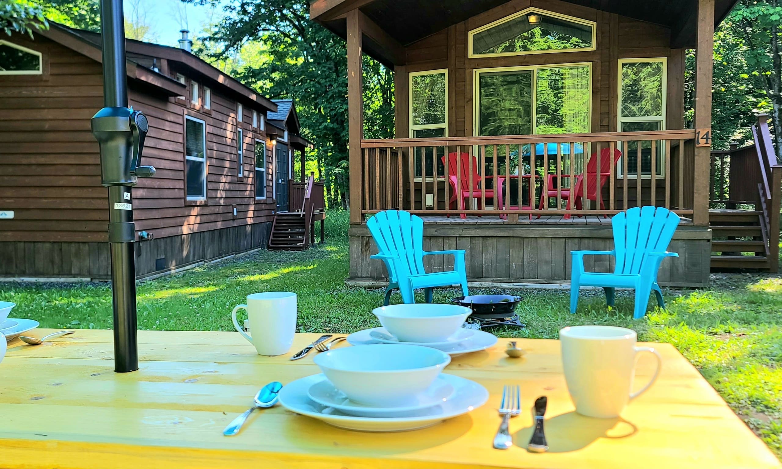 Blue umbrella over a picnic table set for breakfast between two cabins